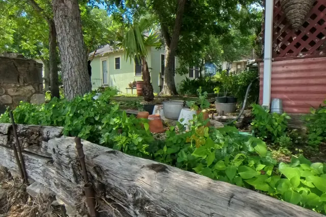 Old stone edging, red lattice, trees, and shaded plants along the Sunken Gardens property.