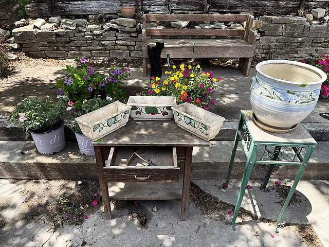 Painted planters, a ceramic pot, and a wood table staged in the courtyard.