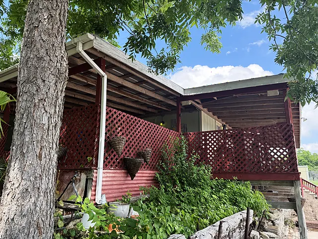 A red lattice porch area with shade and nursery setup materials.
