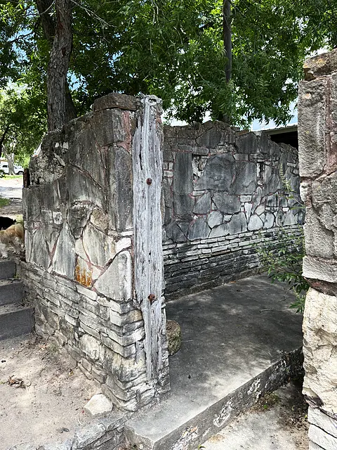 A narrow old stone entry arch and walkway under the trees.