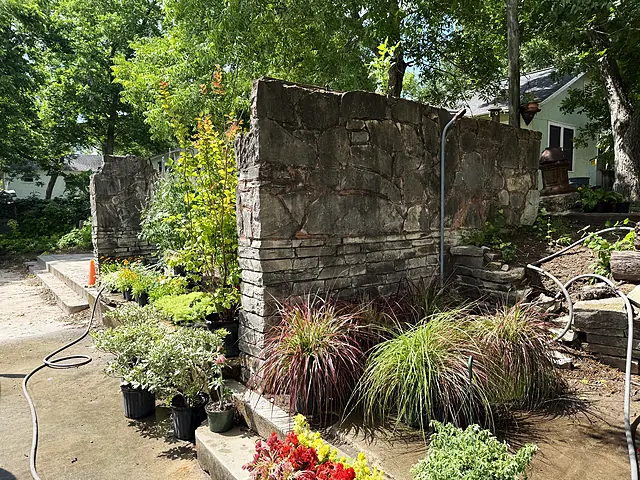 A stone garden entry area with plants and historic masonry.