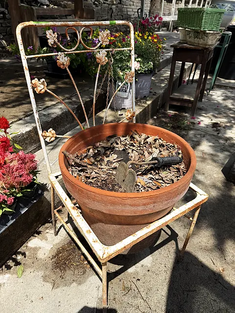 A close view of a rust-colored planter and metal trellis on the patio.