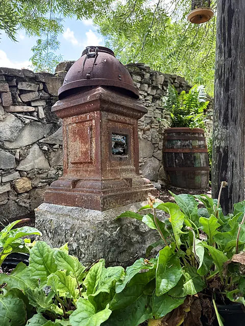 A weathered garden object among stones and leaves.